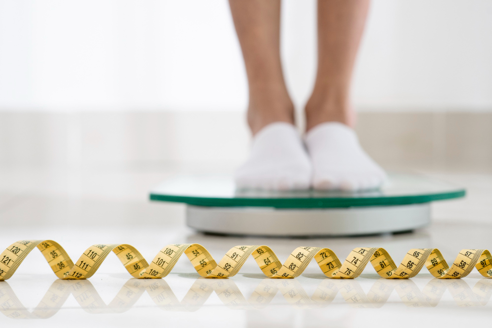 (pies sobre una báscula y en primer plano una cinta de medición)
